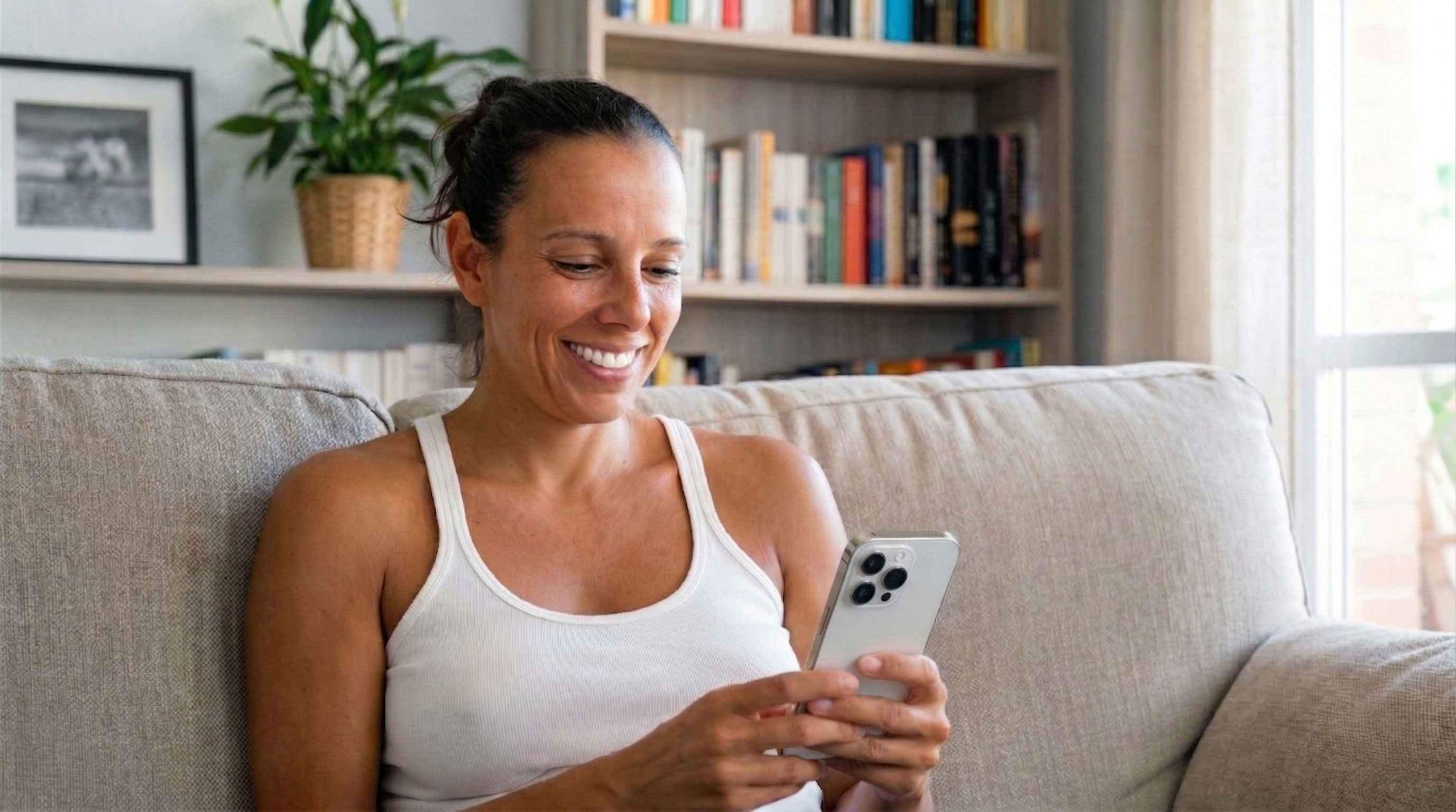 Patient sitting on a sofa using a smartphone while considering 3D simulation options in the Crisalix patient app.